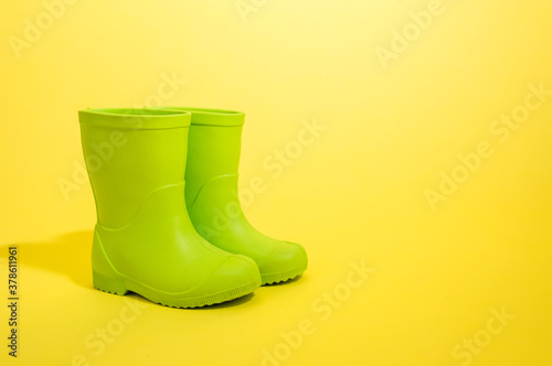 green rubber boots on a yellow background with a copy of the space
