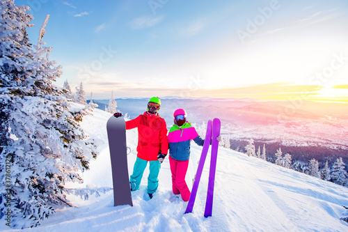 Loving couple snowboarder and skier hold hands on a background of mountains in the winter forest, Sunlight. Concept ski resort