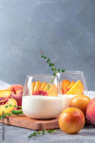 Yoghurt with fresh peaches on light background