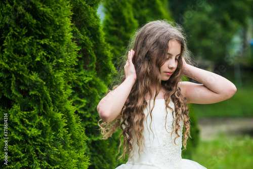 Beautiful girl long curly hair wearing white dress, innocence and tenderness concept