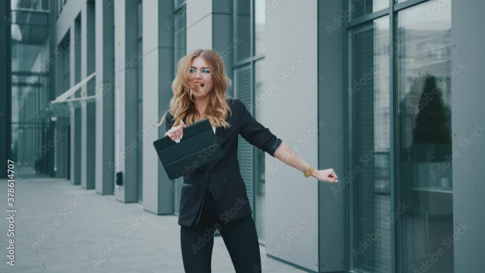 Cute funny young business woman in a business suit look around start to dance near the office building. Entrepreneur. Victory, winner. Corporate. Successful. Cheerful. Happiness. Slow motion. Cute funny young business woman in a business suit look around start to dance near the office building. Entrepreneur. Victory, winner. Corporate. Successful. Cheerful. Happiness. Slow motion.