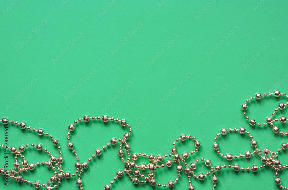 Christmas garland beads in gold on a green background, top view, copyspace