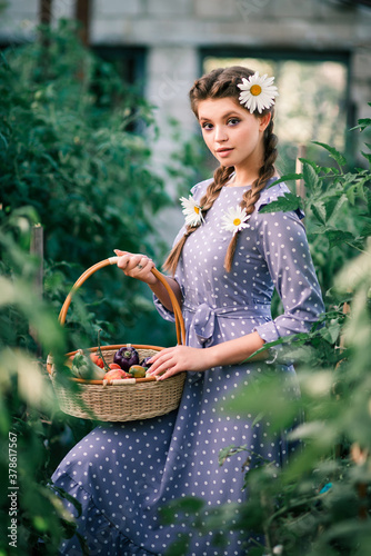 Girl farmer with a basket of vegetables in the garden in greenhouse