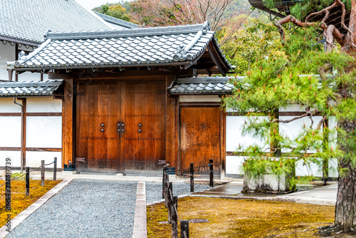 Kyoto, Japan temple shrine building entrance in garden park with green black pine tree and wooden door gate with nobody in path road photo