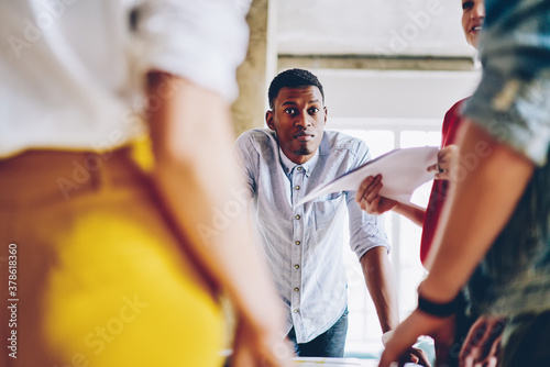 Collaborative process of creative people communicating at business meeting for brainstorming, portrait of dark skinned male looking at camera during briefing cooperation with professional colleagues