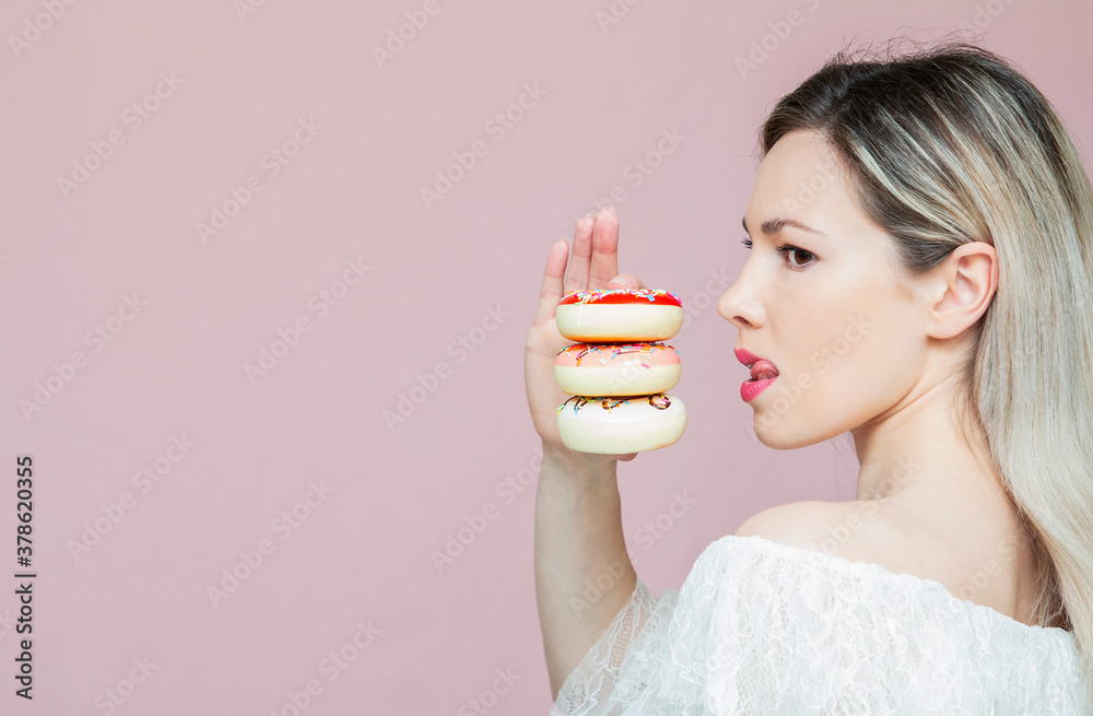 beautiful girl playing with donuts on a pink background. Diet, dieting concept. Junk food, weight loss beautiful girl playing with donuts on a pink background. Diet, dieting concept. Junk food, weight loss