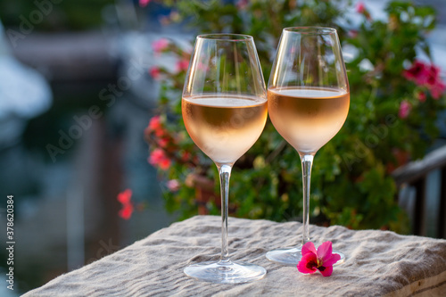 Fototapeta Naklejka Na Ścianę i Meble -  Tasting of local rose wine in summer with sail boats haven of Port Grimaud on background, Provence, France