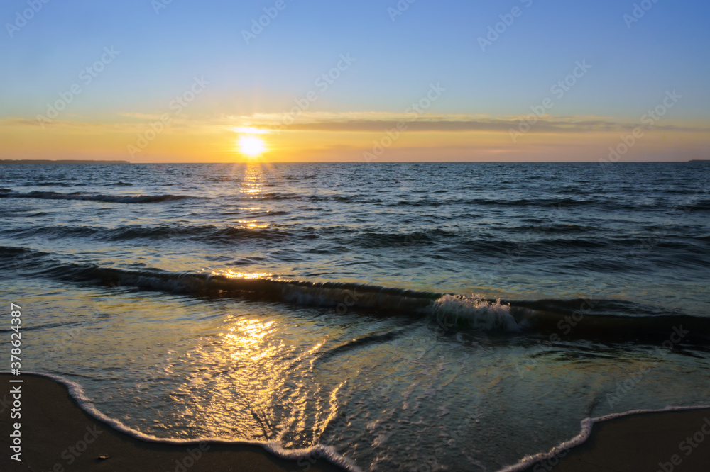 Sunset over the sea. Reflection of sunlight in the sea waves. The sky in the sunset rays.