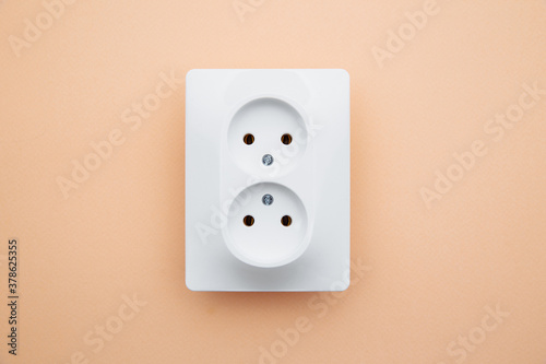 White plastic power socket on pink background. Top view.