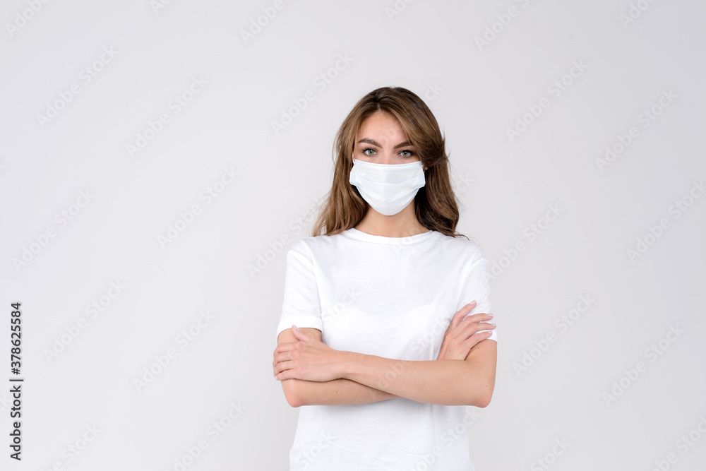 Woman wearing face mask holding her hands crossed on the chest against white studio background Woman wearing face mask holding her hands crossed on the chest against white studio background