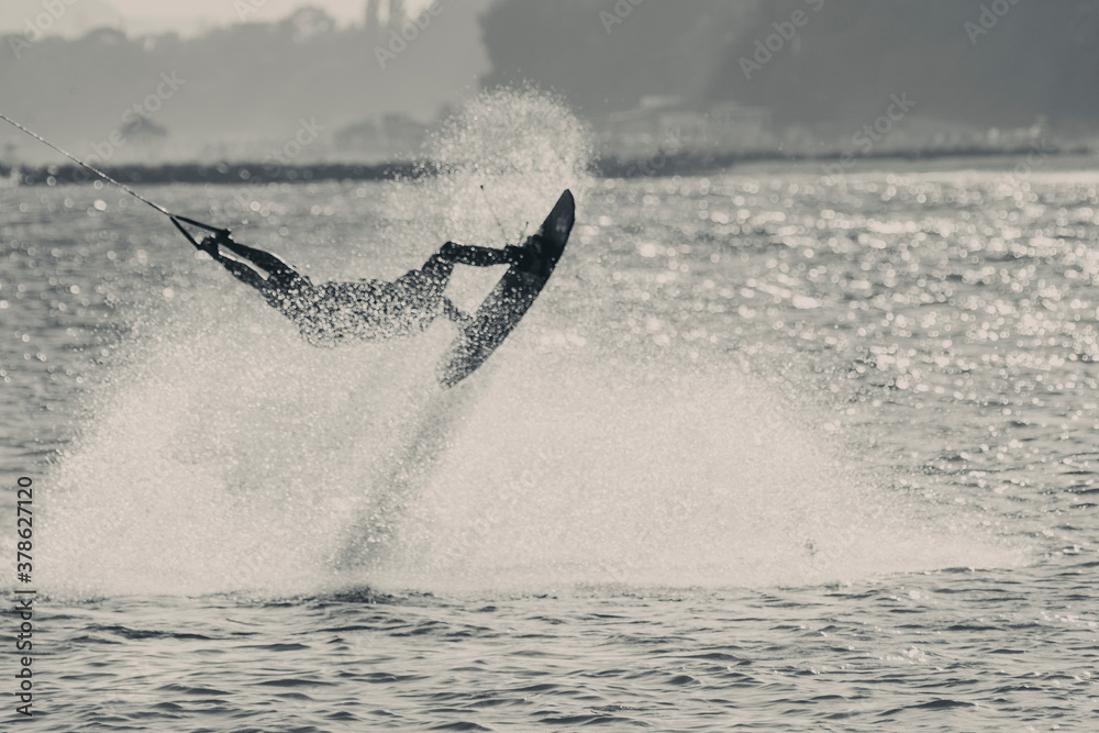 Fototapeta premium WAKEBOARDING AT THE SEA JUMPING HIGH DOING A BACKFLIP IN BLACK AND WHITE