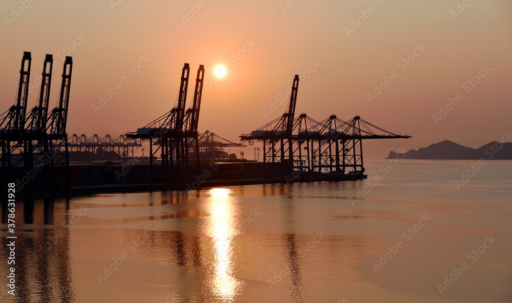 Industrial background - sunrise over the sea port with gantry cranes. 