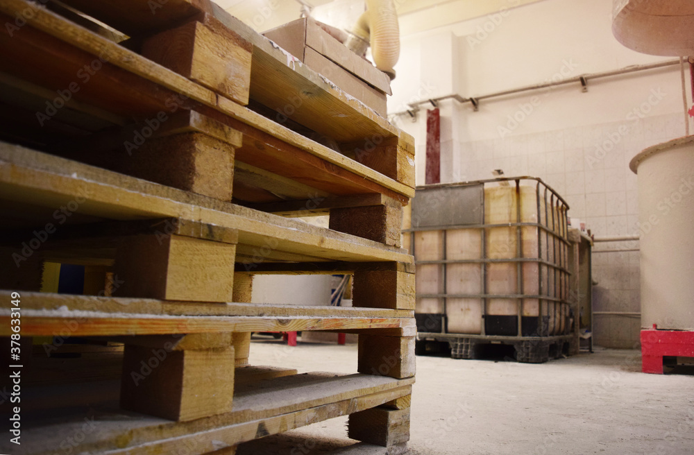 Wooden pallets stacked in a production area. Workshop for the production of paint. Wooden pallets stacked in a production area. Workshop for the production of paint.