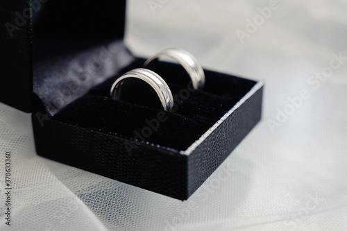 Wedding rings lie in a black heart-shaped case.