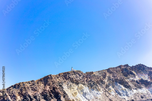 Cliff and lighthouse on the southern of Thira island in Greek Islands on a clear, sunny day with bright, blue sky. Akrotiri, Santorini, Greece. Akrotiri