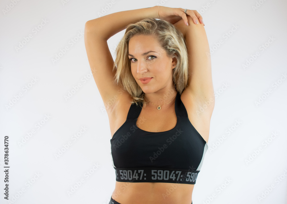 Obraz premium Pretty young woman standing and doing stretching exercises in ballet studio
