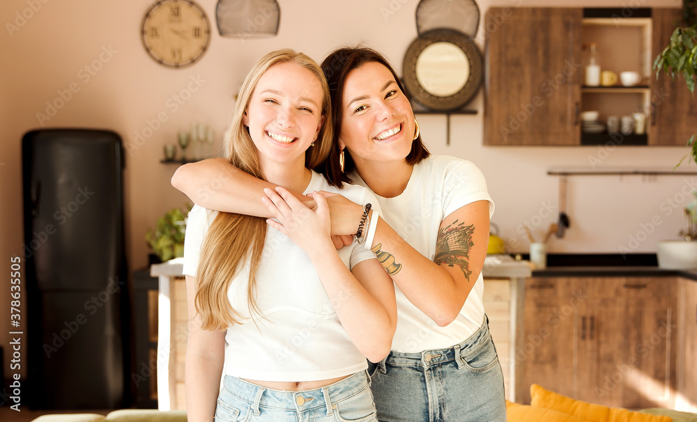 © AliceCam - Two women friends hugging at home. Adorable lesbian couple. Best friends, affectionate and happy.
