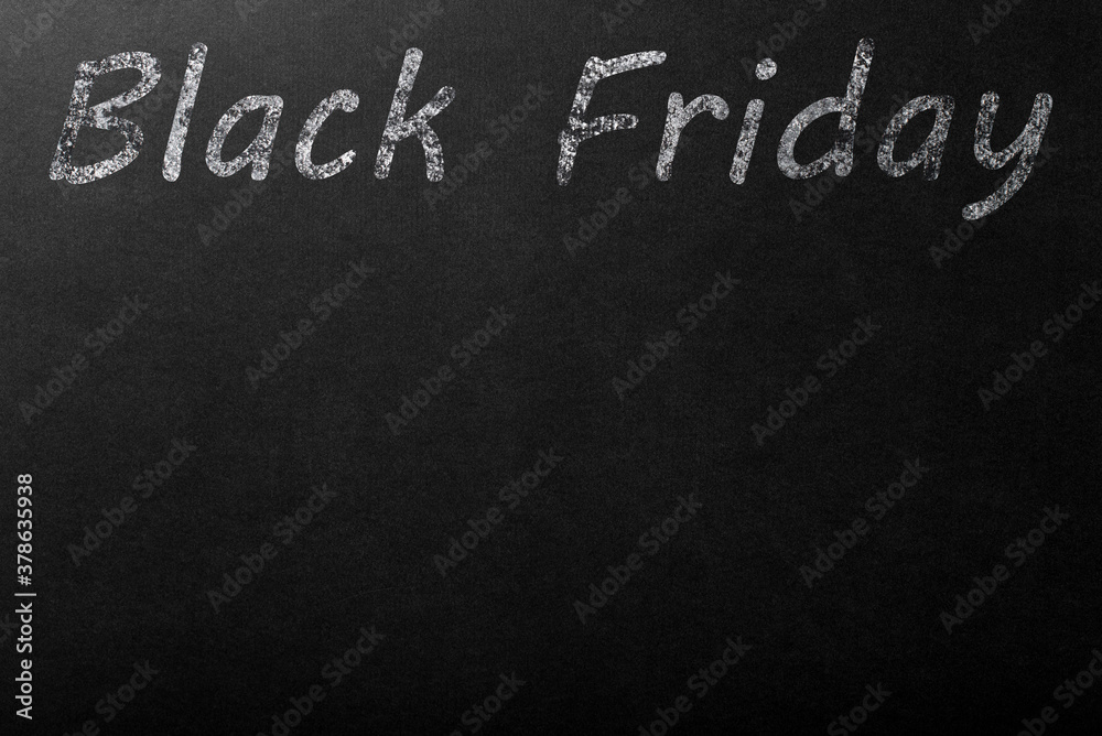 Fototapeta premium The inscription Black Friday in white chalk on a dark blackboard. Copyspace on a black background.