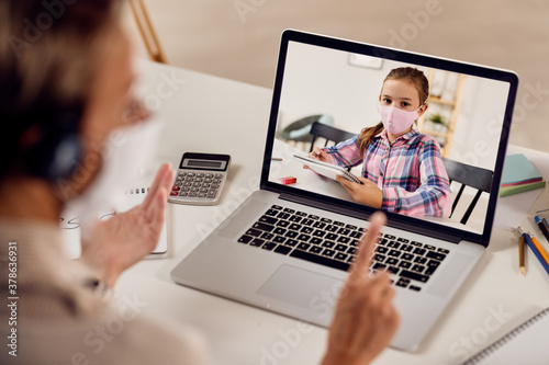 Close-up of teacher making video call over laptop with her small student due to COVID-19 epidemic.