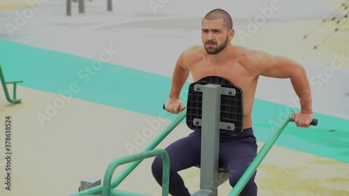 Saint Petersburg, Russia, Yuzhnaya Doroga street, August 21, 2020. Athletic man has a beautiful body, trains on the Playground in the summer on the street. photo