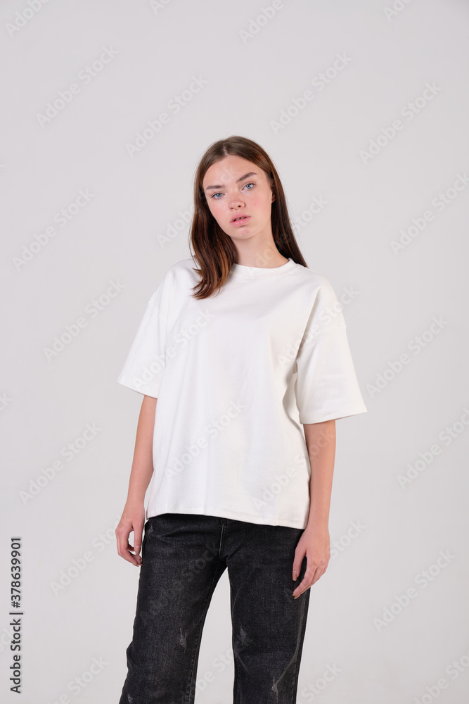 Fashion model dressed in casual white t-shirt and black pants posing in the studio for Look book and clothing catalog.
