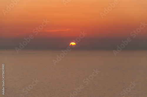 Sun disappearing behind the clouds as it sets over the sea in Zakynthos island  Greece