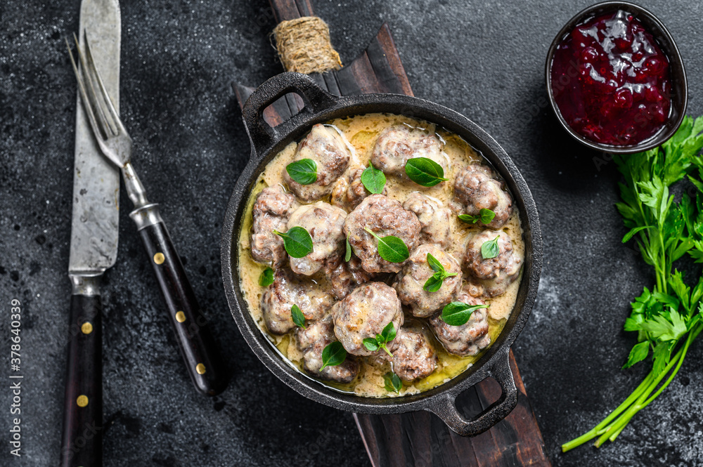 Swedish meatballs with lingonberry sauce in a frying pan. black background. Top view