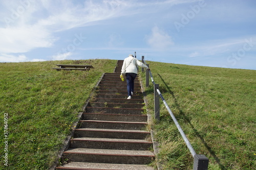 Walking on the stairs on Dutch dyke, seawall as protection against the North Sea (Hondsbossche Zeewering). Netherlands, September. © Thijs de Graaf