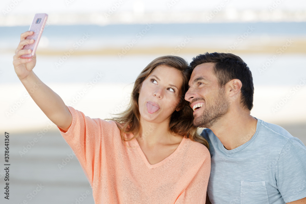 couple taking selfie with a phone and making silly faces
