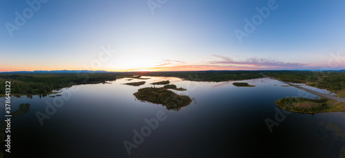 Picturesque Aerial View of Canadian Scenic Island surrounded by Peaceful Lakes. Vibrant summer sunset on the horizon. Cariboo Highway, Interior British Columbia.