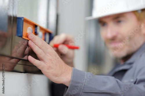 Canvastavla man measuring wooden wall with level and pencil