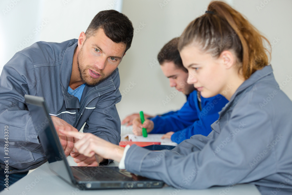 young female mechanic pointing at laptop young female mechanic pointing at laptop