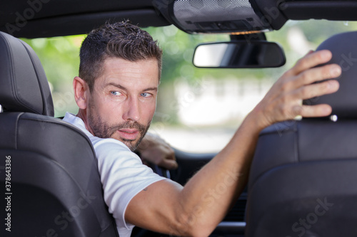 Фотография driver turning in his seat to look behind to reverse