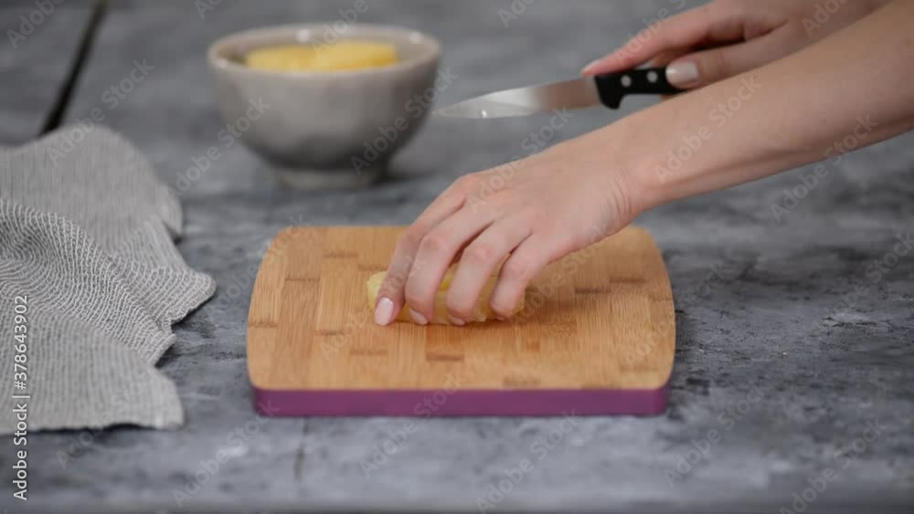 Woman hands cutting pineapple on small pieces.