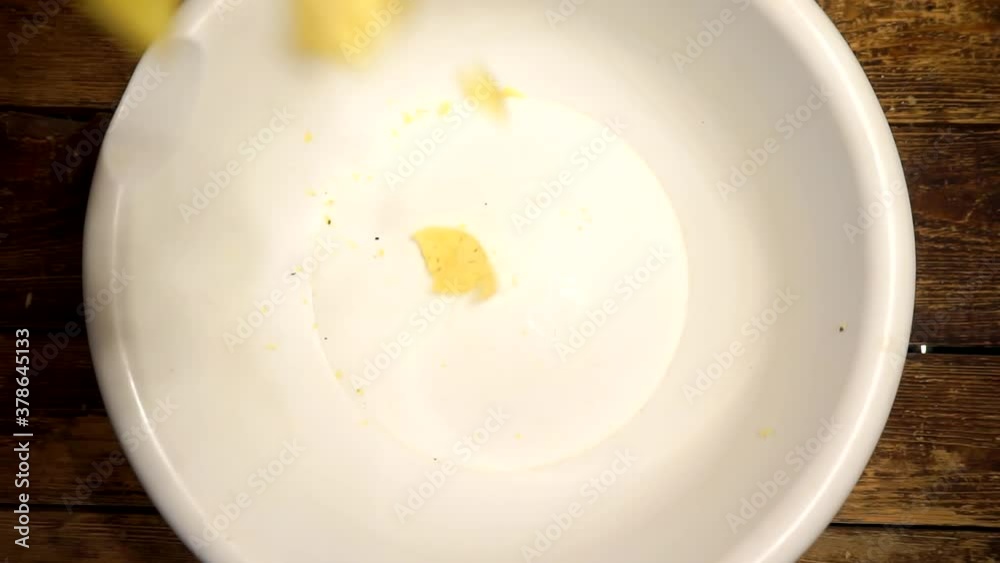 appetizing fried yellow potato chips falling into a plastic bowl appetizing fried yellow potato chips falling into a plastic bowl