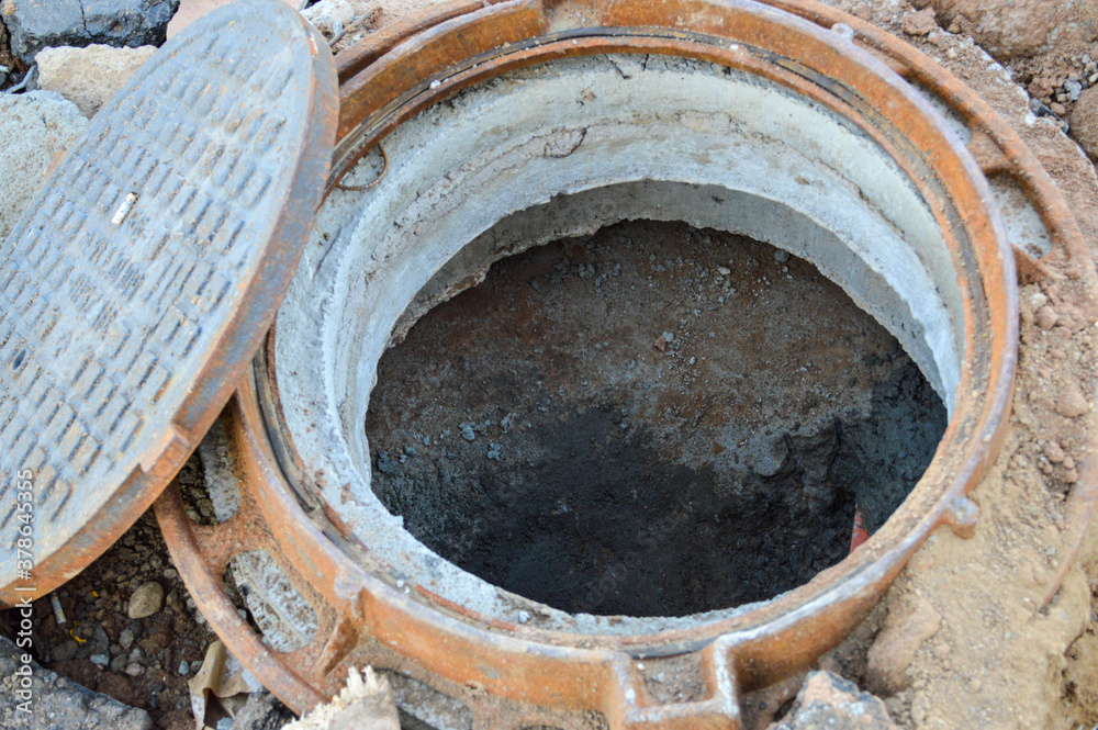 open sewer on the street. metal tunnel for water drainage, creating a sewer passage. rusty manhole cover, construction hole. sewerage at the construction site. production of a new residential complex