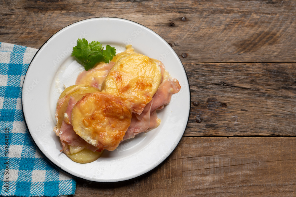 Scalloped potatoes with ham and cheese on wooden background Scalloped potatoes with ham and cheese on wooden background