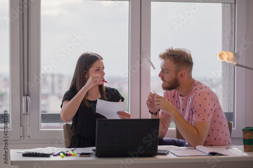 two young people, discussing project together. casually dressed in apartment.