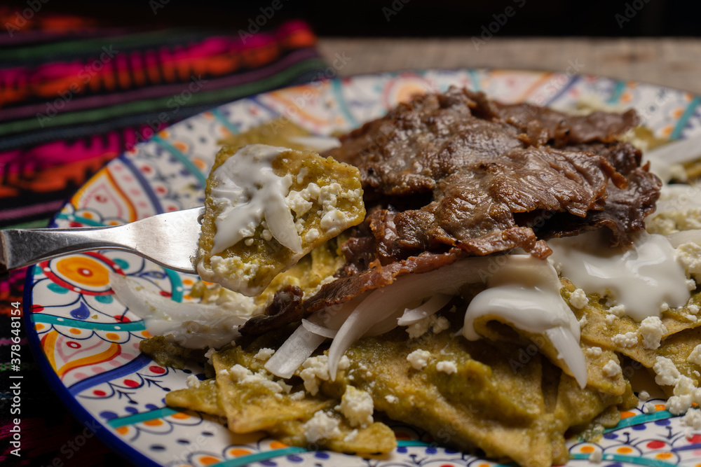 Mexican green chilaquiles with cecina beef steak on wooden background