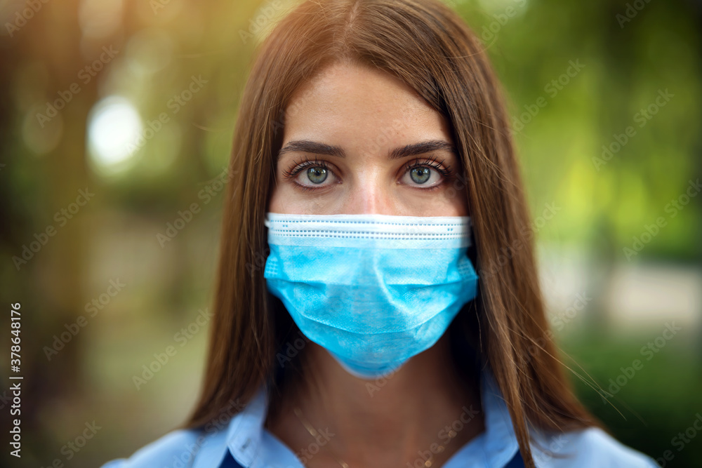 Authentic close up shot of an young woman is wearing a medical mask to protect herself from disease is looking in camera in green park. Authentic close up shot of an young woman is wearing a medical mask to protect herself from disease is looking in camera in green park.