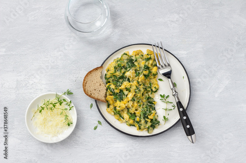 Scrambled eggs with kale and cheese on a light gray background, top view. delicious homemade breakfast	 photo