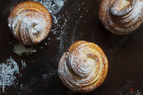 Three fresh kraffins on a dark table with powdered sugar photo