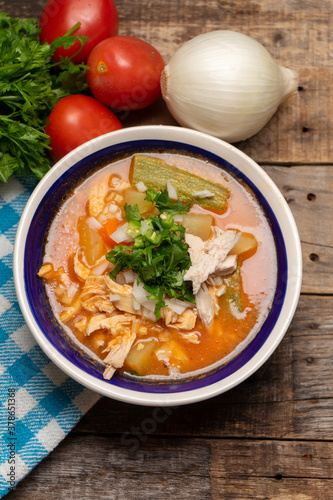 Mexican chicken soup with vegetables and rice on wooden background