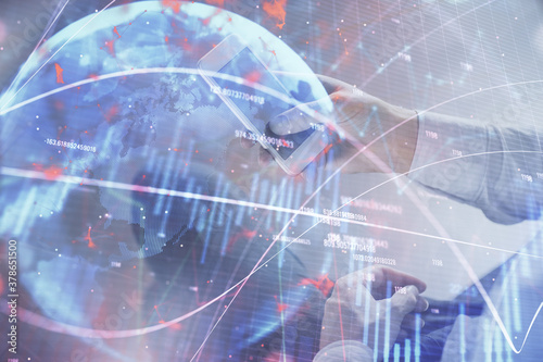 Double exposure of man's hands holding and using a digital device and forex graph drawing. Financial market concept.