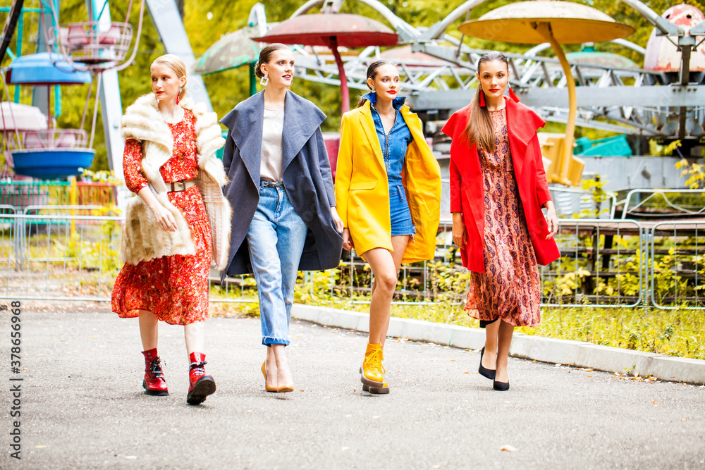Naklejka premium Four fashion models walking in autumn park