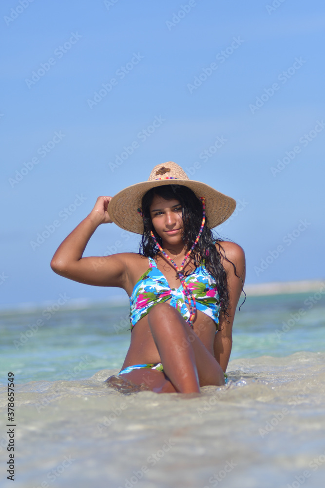 African American Woman siting on beach inside blue water splash. Natural laughing holding straw hat , Beach Beach Background