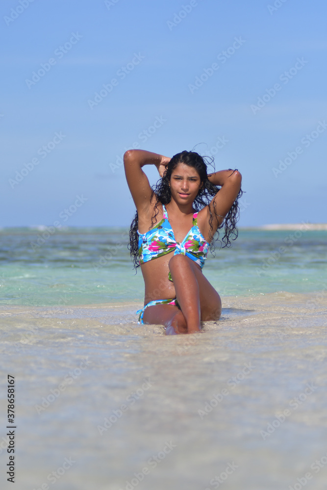 Sensual Hispanic young woman siting inside water waist up stroke her long black hair