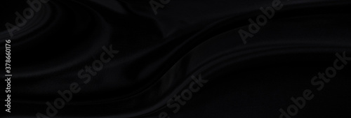 Black gray satin dark fabric texture luxurious shiny that is abstract silk cloth panorama background with patterns soft waves blur beautiful.