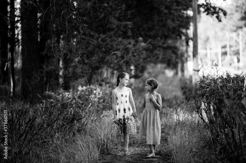 Two girlfriends ten-year-old girls walk in the park. Black and white photo.