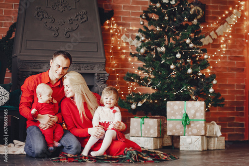 Beautiful mother in a red dress. Family sitting near christmas gifts. Little girl and boy near christmas tree